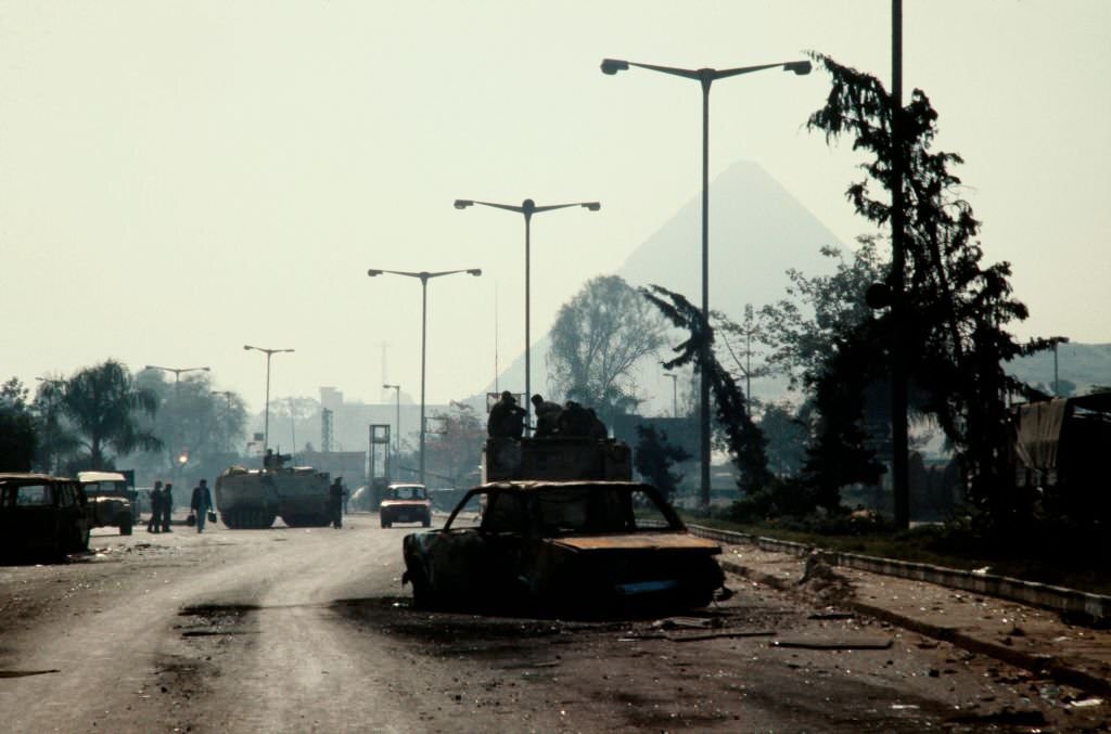 #10 A burned out car lies on the road after the protest and police riot in Cairo on February 26, 1986.