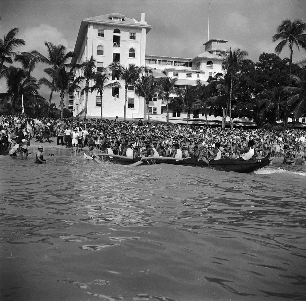 #24 Crowds gather on the Hawaiian island of Oahu to watch the winning boat of a gruelling 36 mile canoe race arrive at the finish, 1950