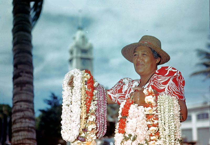 #1 Hawaiian woman selling lei with Aloha Tower in the background, Honolulu Harbor, Oahu, Hawaii