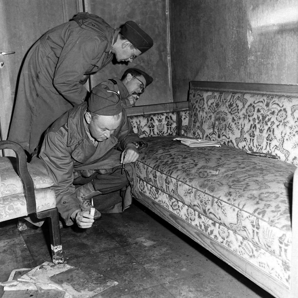 #5 With only candles to light their way, war correspondents examine a couch stained with blood (see dark patch on the arm of the sofa) located inside Hitler’s bunker.