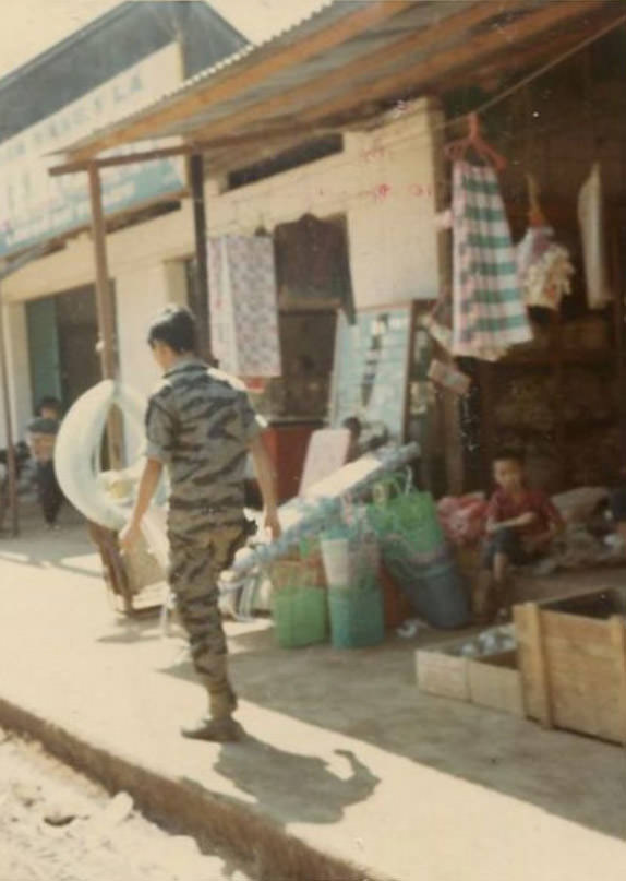 #10 An unidentified South Vietnamese Army (ARVN) soldier walking past a store somewhere in the city of Bồng Sơn in South Vietnam.