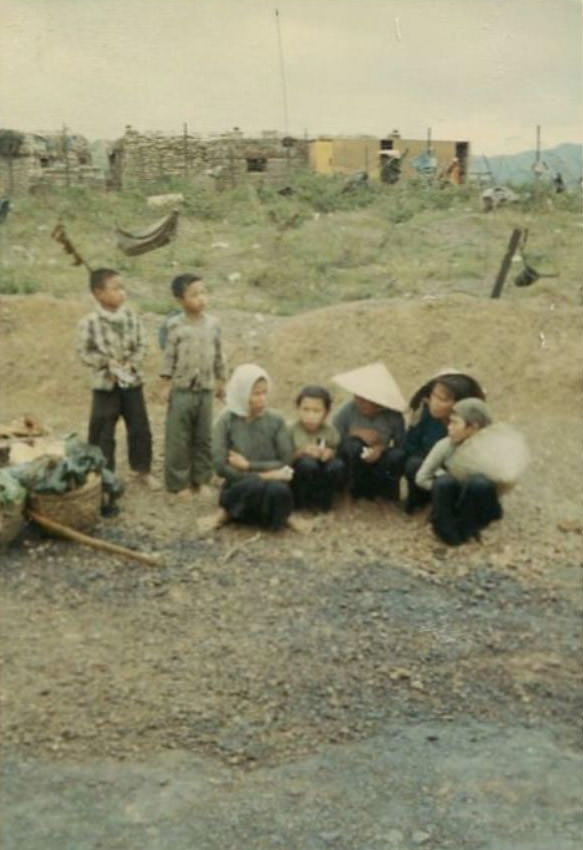 #24 Several Vietnamese women and children, considered prisoners, sitting on the ground near the helicopter landing area of the 2nd Battalion.