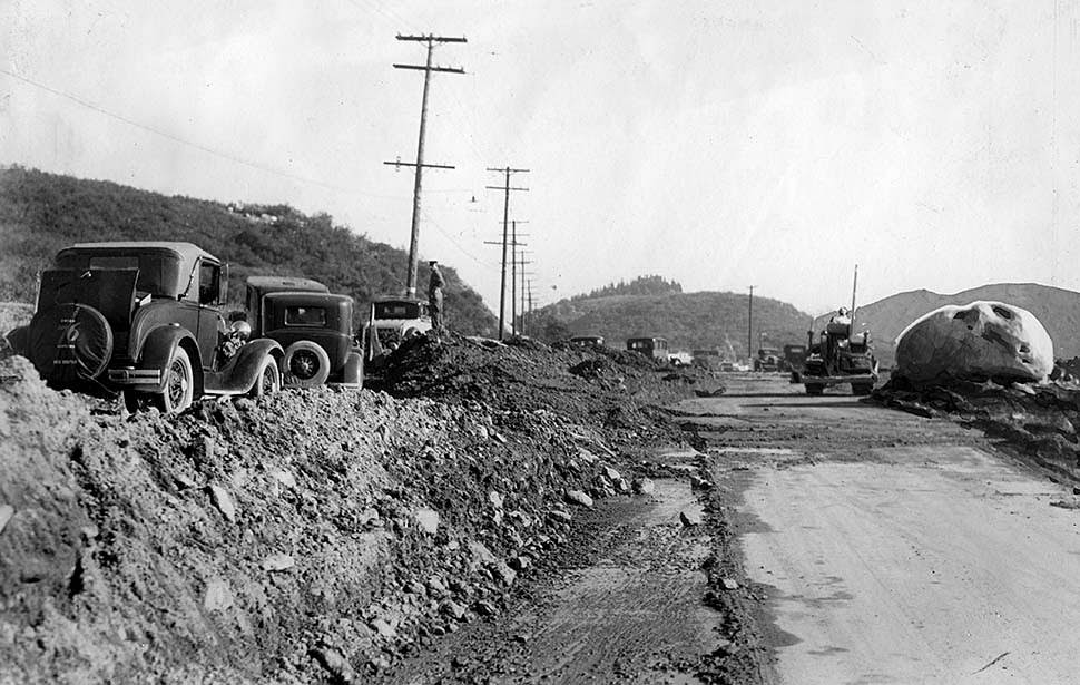 #13 Cars parked on the dirt, left, show the depth of debris on roadway being cleared on Foothill Boulevard in Montrose, 1934