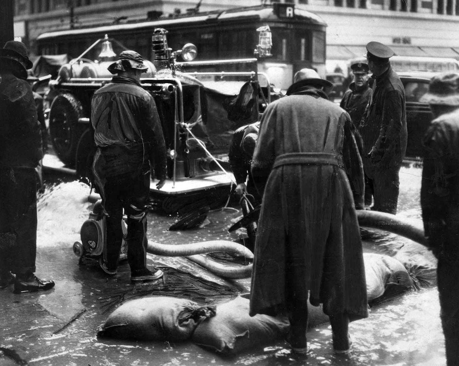 #24 Water rising above the drain level in underground conduits threatened telephone service in downtown Los Angeles. Fire Department pumpers answered the call, 1938