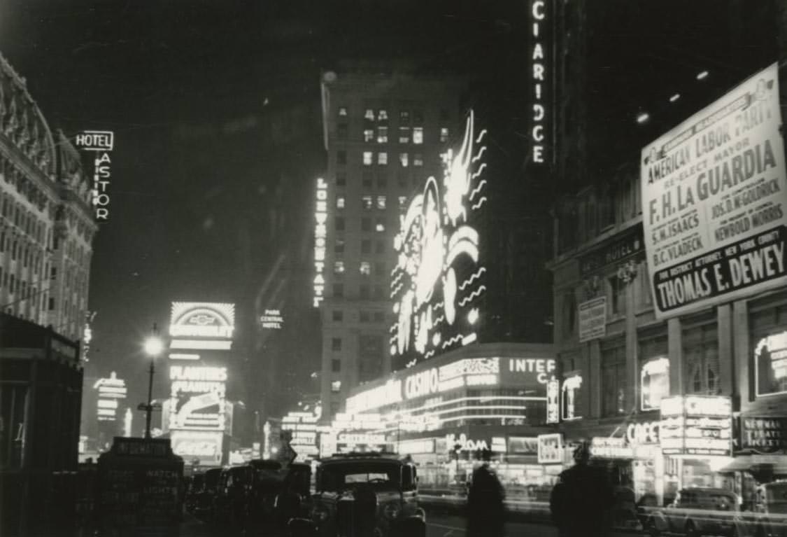 #39 Broadway north of 42nd Street at night in Times Square with Astor Hotel to the left and an American Labor Union Party sign for Mayor F.H. La Guardia’s re-election to the right.