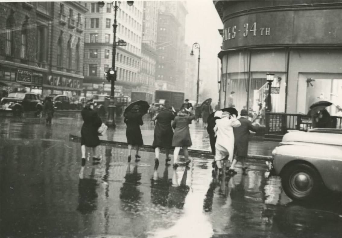 #12 Pedestrians cross the street in the rain towards Saks – 34th store on West 34th Street in Midtown Manhattan