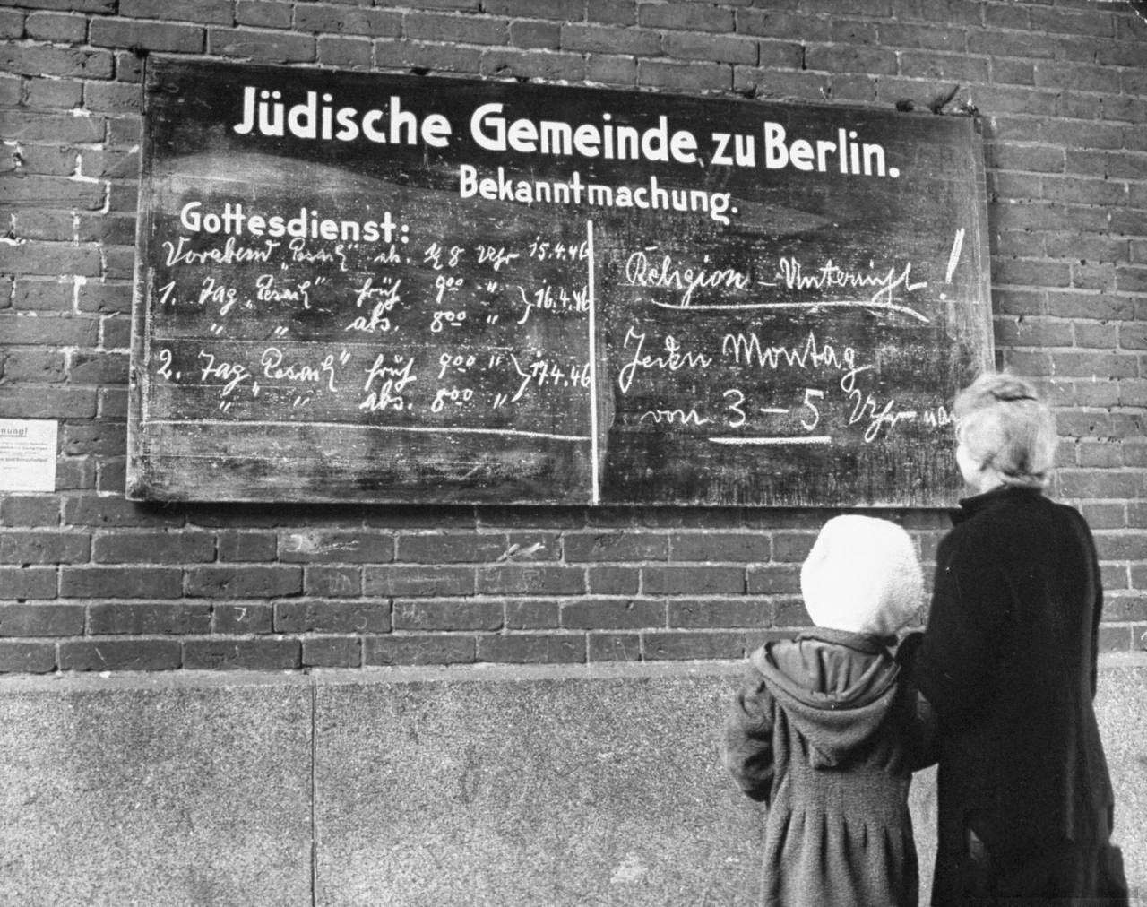 #2 A woman and her child reading the bulletin board outside a synagouge during Passover.