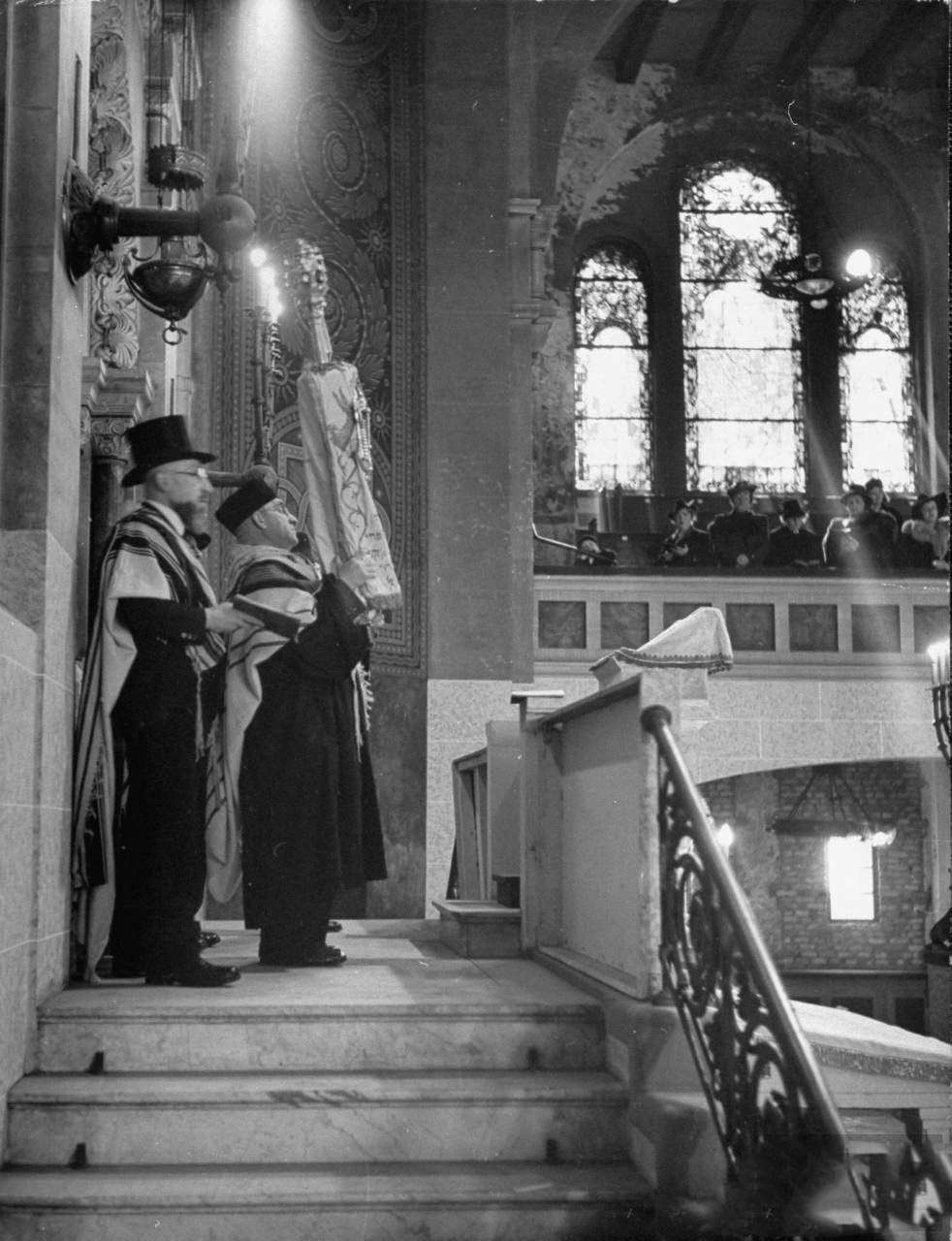 #7 Chief Cantor Ruschin holding Torah scrolls up to the worshipers at the synagogue during Passover.