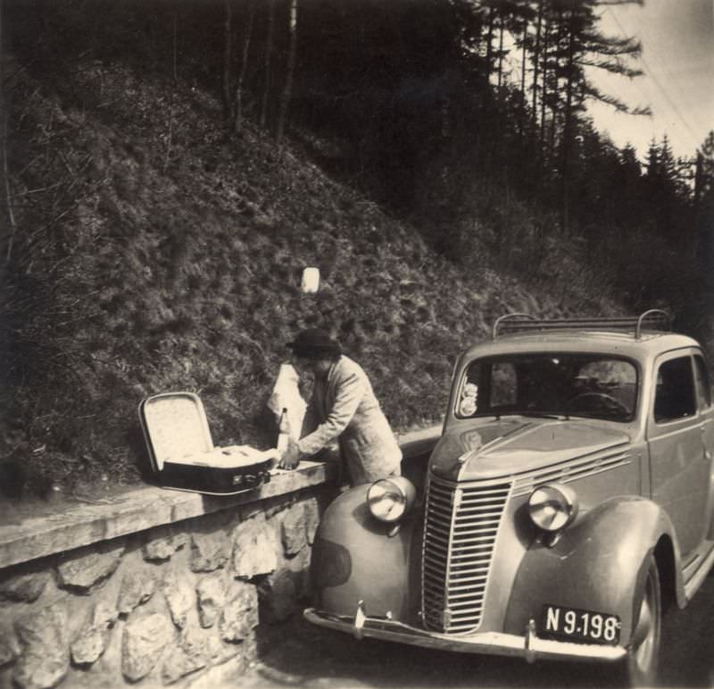 #13 A lady preparing a roadside picnic next to a Fiat 1100 on a mountain road, 1950