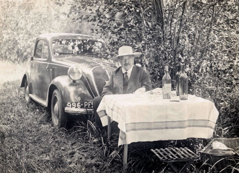 #9 A middle-aged fellow in a suit and tie posing at a picnic table in the countryside, 1938