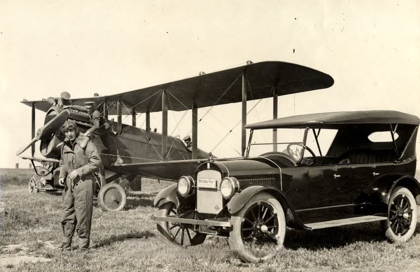 #75 Eddie Rickenbacker with biplane and automobile, 1925