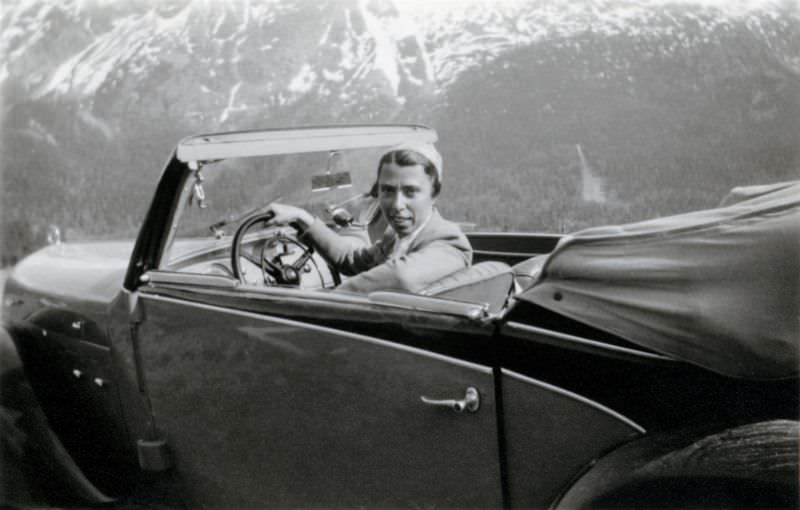 An elegant lady posing in the driver’s seat of a two-tone Steyr 120 Super in an Alpine setting, 1938