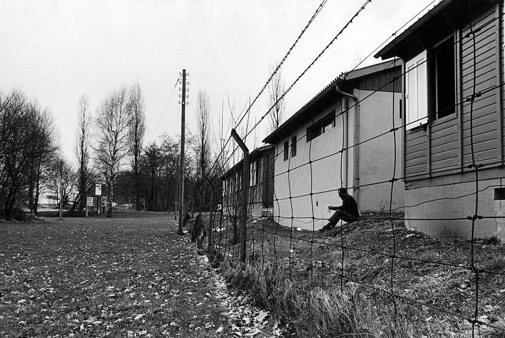 #60 An Italian emigrant reading a letter among cabins surrounded by barbed wire. Zurich, 1971