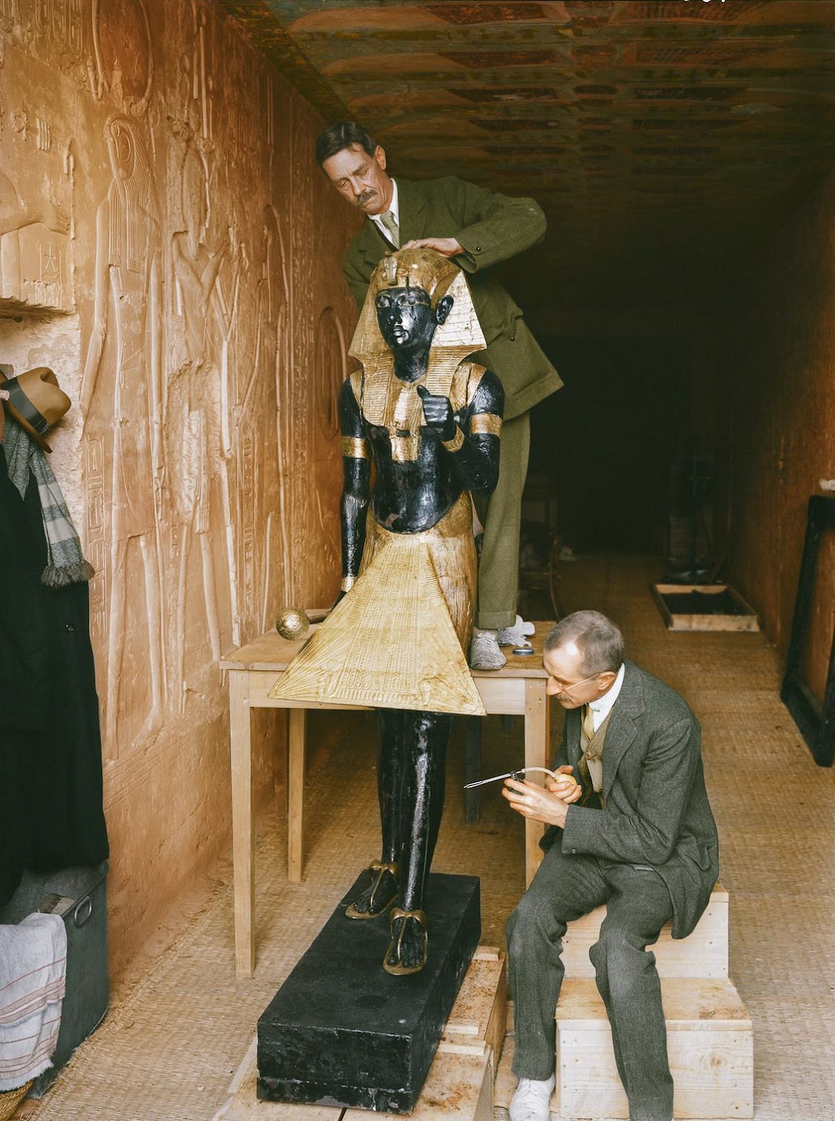 Arthur Mace (standing) and Alfred Lucas (sitting) working inside the makeshift ‘laboratory’ (set up in KV 15, the tomb of Sethos II) on the conservation of one of the two sentinel statues from the Antechamber (Carter no. 22). Sethos II’s Tomb, 4th January 1923