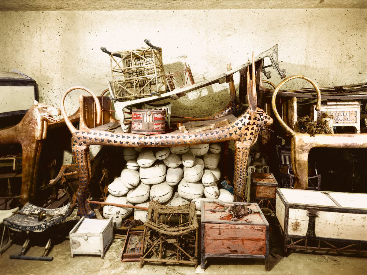 Objects, including the cow-headed couch (Carter no. 73) and boxes containing joints of meat (Carter nos. 62a to 62vv) piled up against the west wall of the Antechamber. Tutankhamun’s Tomb, December 1925