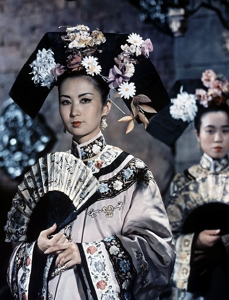 A woman fans herself in a scene from the film ’55 Days At Peking’, 1963.