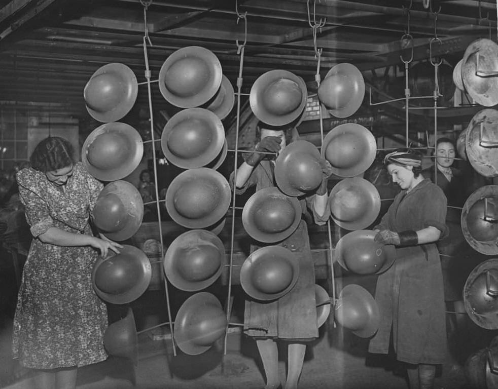 #10 Women workers hang out tin hats which have just been spray painted, to dry, 1940.