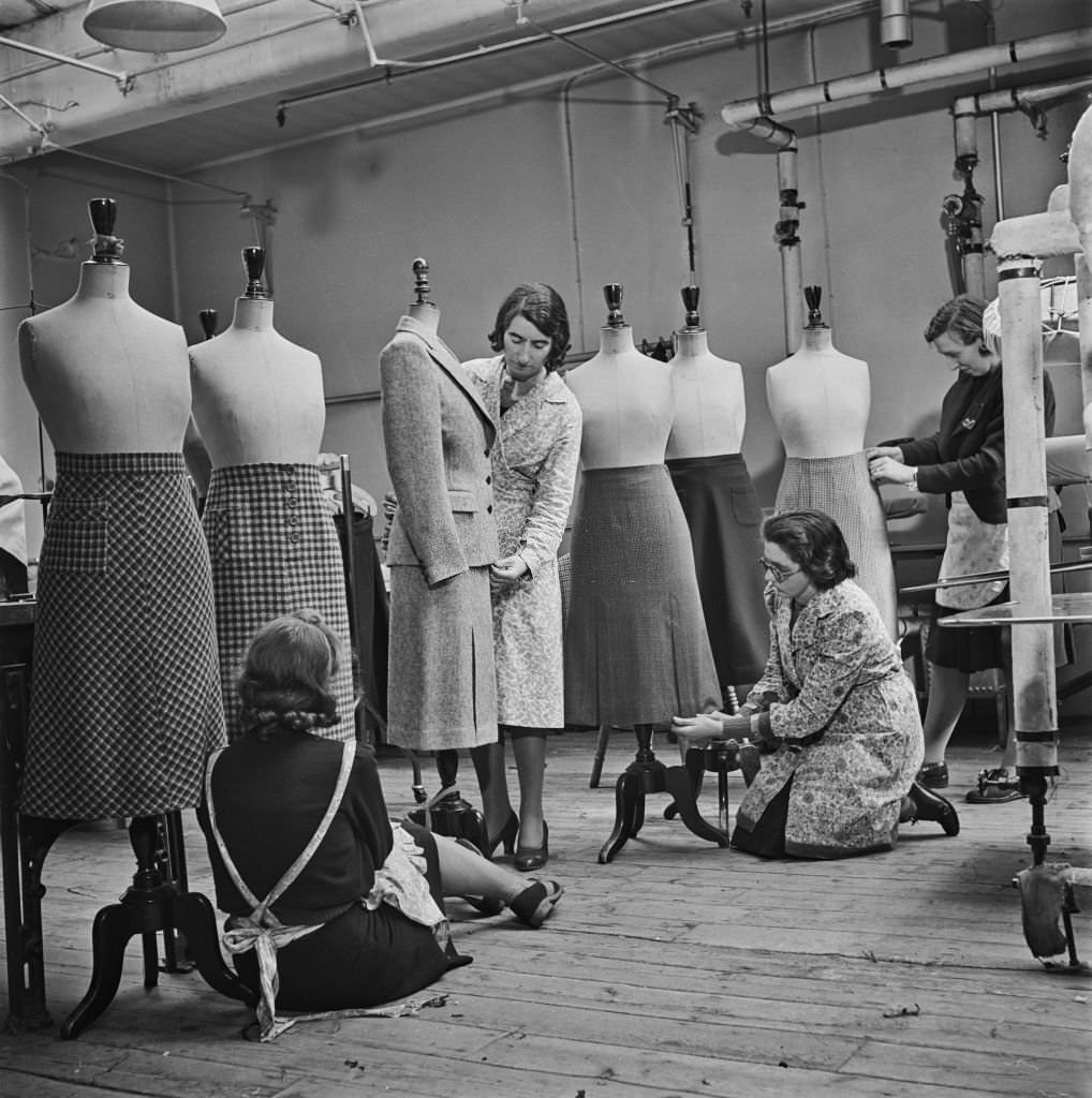 #124 Four seamstresses make final adjustments to utility suits and skirts at a Bourne and Hollingsworth department store workroom in London during World War II.