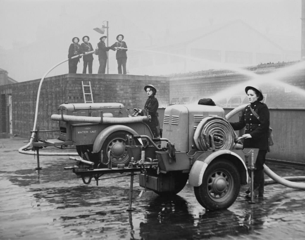 #127 Members of the first all female Auxiliary Fire Service (AFS) fire station in Northumberland undergo training with a portable 80lb water pressure hose and pump powered by a Coventry Climax engine on 3rd February 1942 in Glasgow.