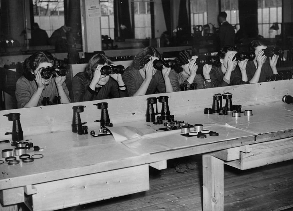 #13 Workers in one of the largest optical instrument making factories in Britain, where binoculars, telescopes, photographic lenses and other scientific devices are made for the armed forces.