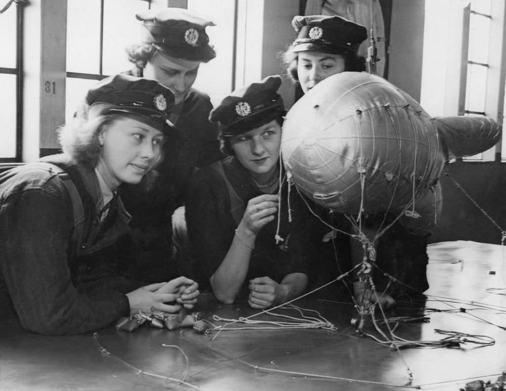 #140 Members of the Women’s Auxiliary Air Force (WAAF) using a model to study the construction of barrage balloons, UK, 11th September 1941.