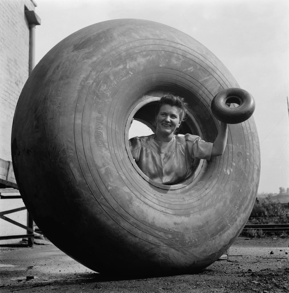 #145 A woman inside a Dunlop aeroplane tyre and holding a smaller tyre in Birmingham, England, during World War II, August 1941.
