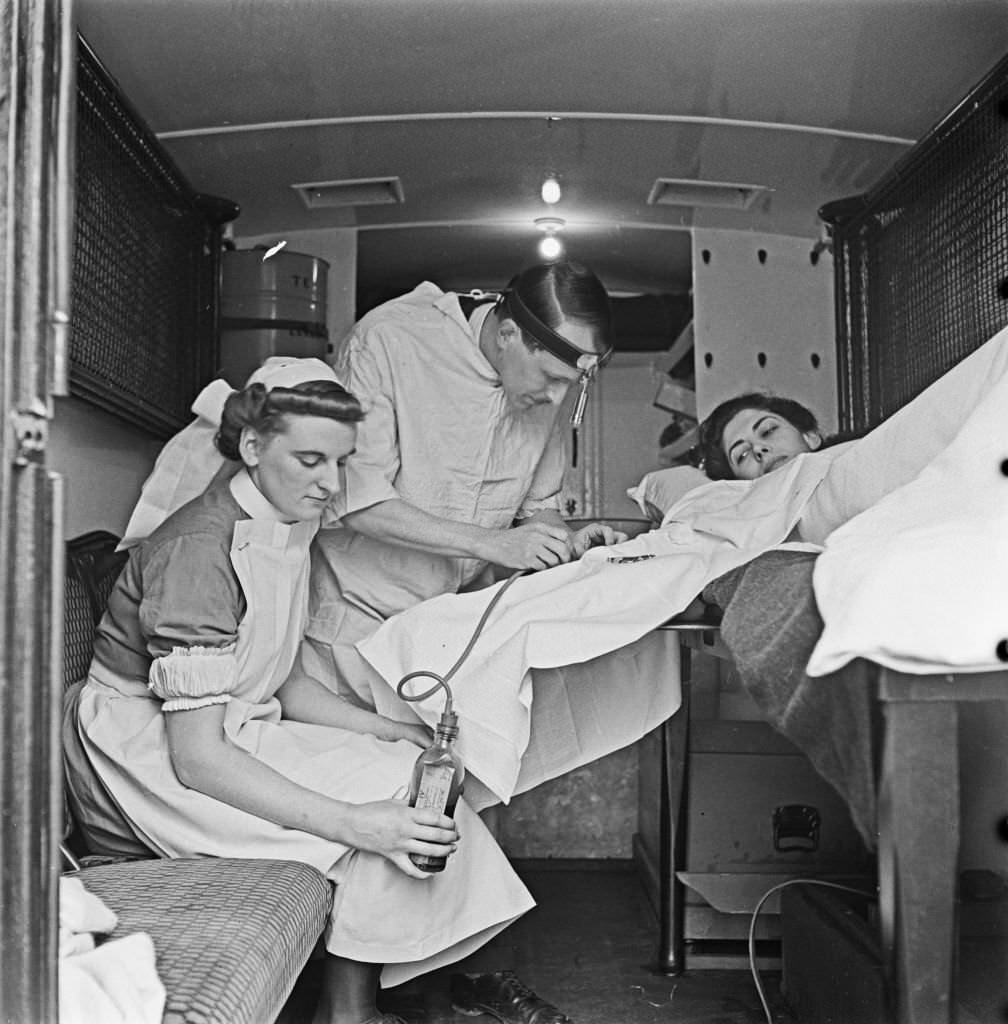 #157 Nurse Marjorie Harrison and Doctor W Stanbury administer a transfusion of blood to a patient lying in an ambulance Great Britain vehicle following a German Luftwaffe air raid over the city of Ripon in Yorkshire.