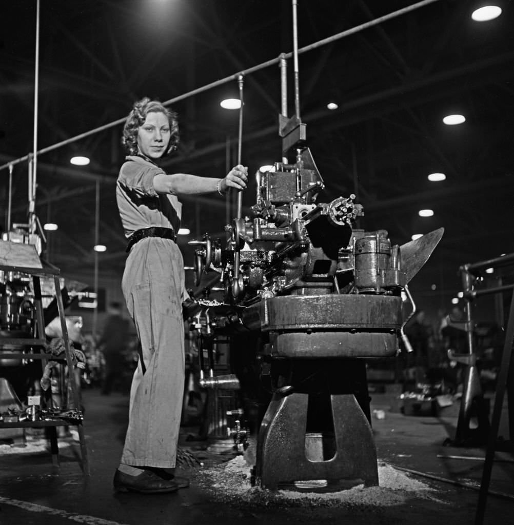 #159 A skilled female munitions worker at work on her metal working lathe to produce parts for Supermarine Spitfire fighter aircraft at an aircraft factory in England, 1941.