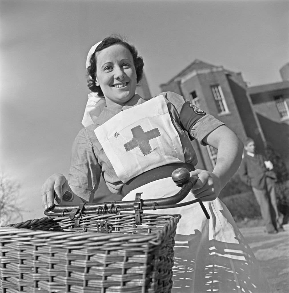 #164 Nurse M S Sparkes uses a bicycle to cycle through the grounds to her ward at Shenley Hospital, a military hospital at Shenley near St Albans in Hertfordshire, England during World War II on 24th March 1941.