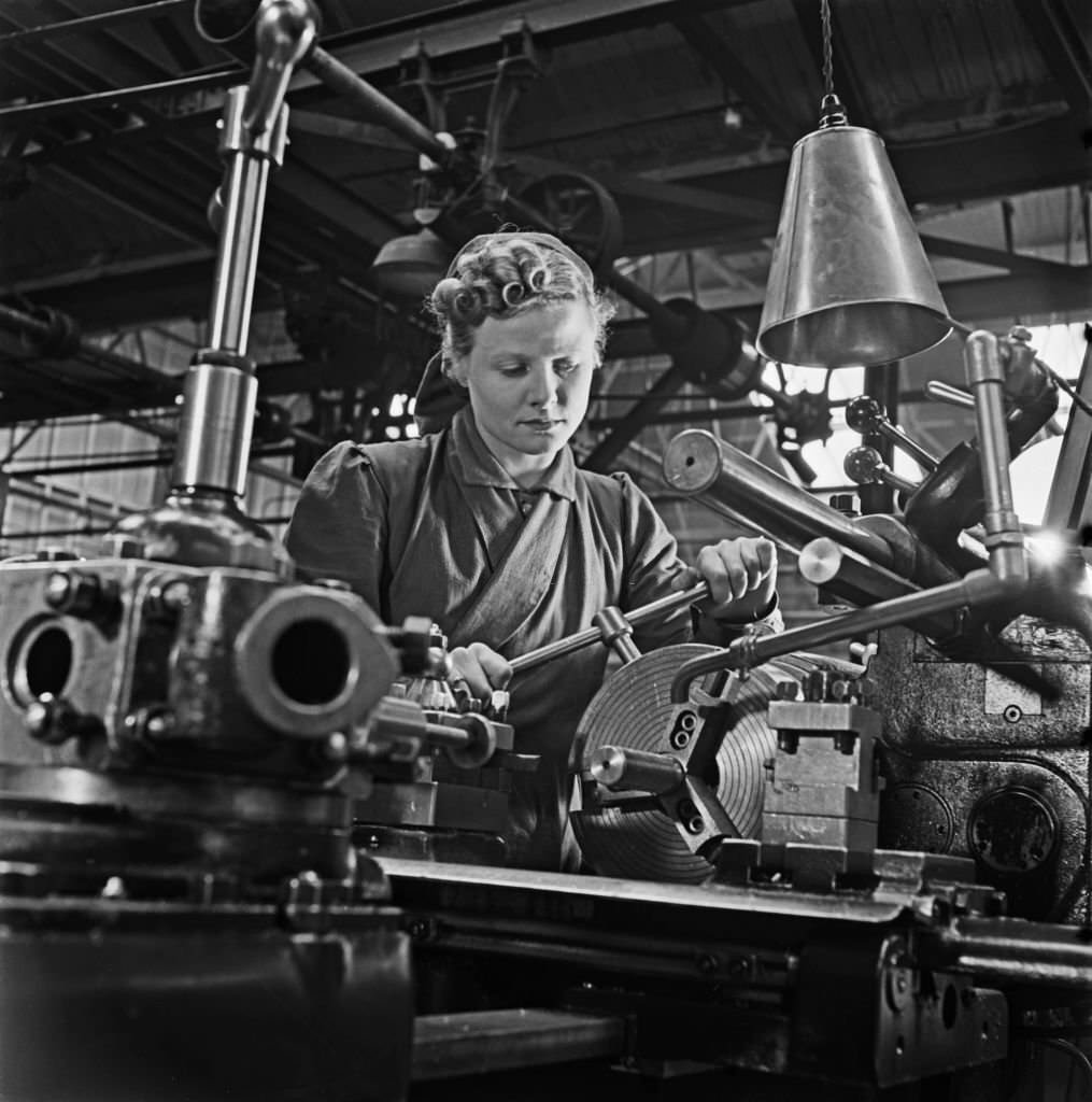 #166 Trainee munitions worker Muriel Maggs, a former cinema usherette, operates a capstan lathe at a British Government training centre in Reading, England, 31st March 1941.