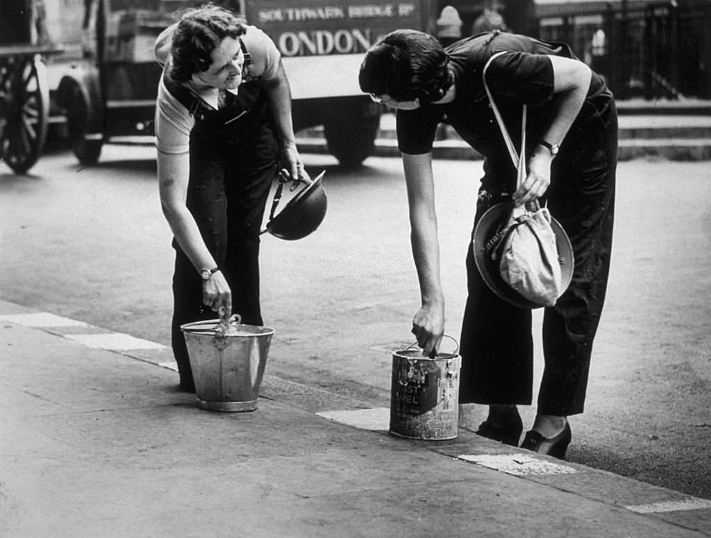 #29 Ambulance workers paint the street kerbs white in order to assist them to drive at night from their London depot, 1939