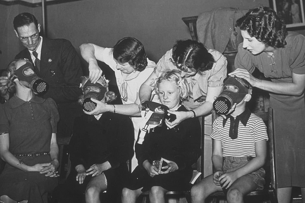 #31 Three children and a young woman being fitted for gas masks, 1939