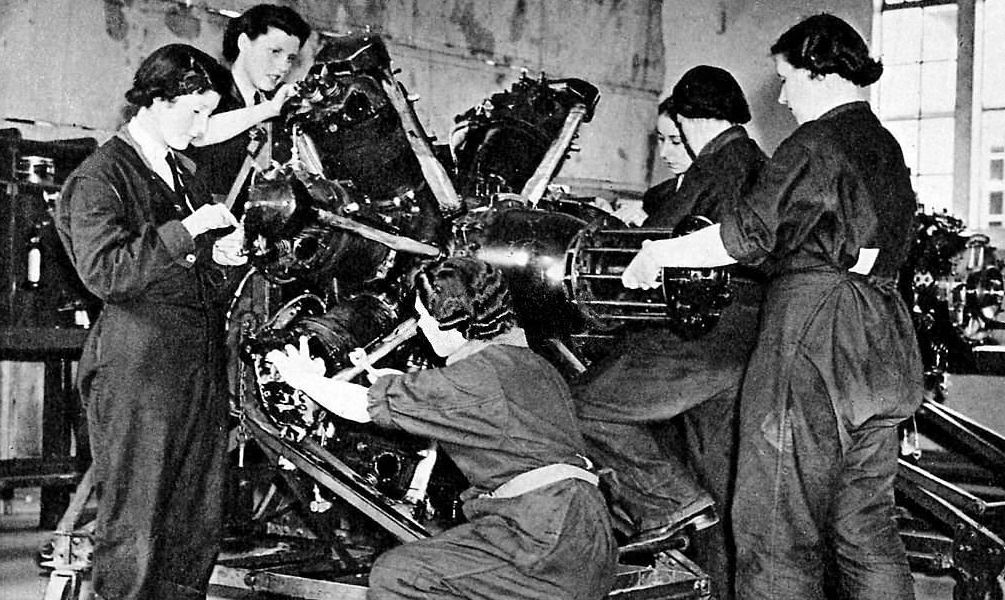 #48 Women’s Auxiliary Air Force (WAAF) – Female mechanics in training. A group of women in overalls study the construction of a radial dial engine.
