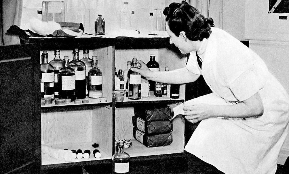 #49 Women’s Auxiliary Air Force (WAAF) – A nurse takes a bottle from a medicine cabinet.