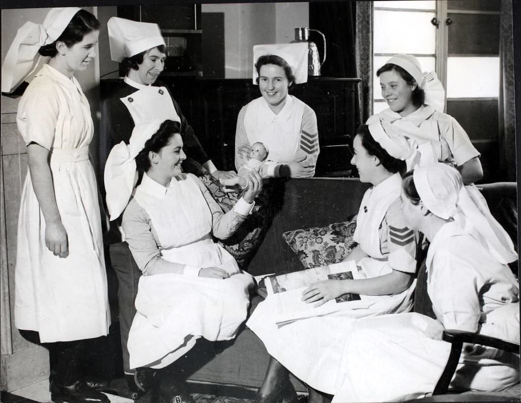 #60 A small baby doll causes some amusement amongst the nurses as they taken a few minutes off in their comfortable rest room at the St. Charles’s Training Centre in London, England, World War II, December 1941.