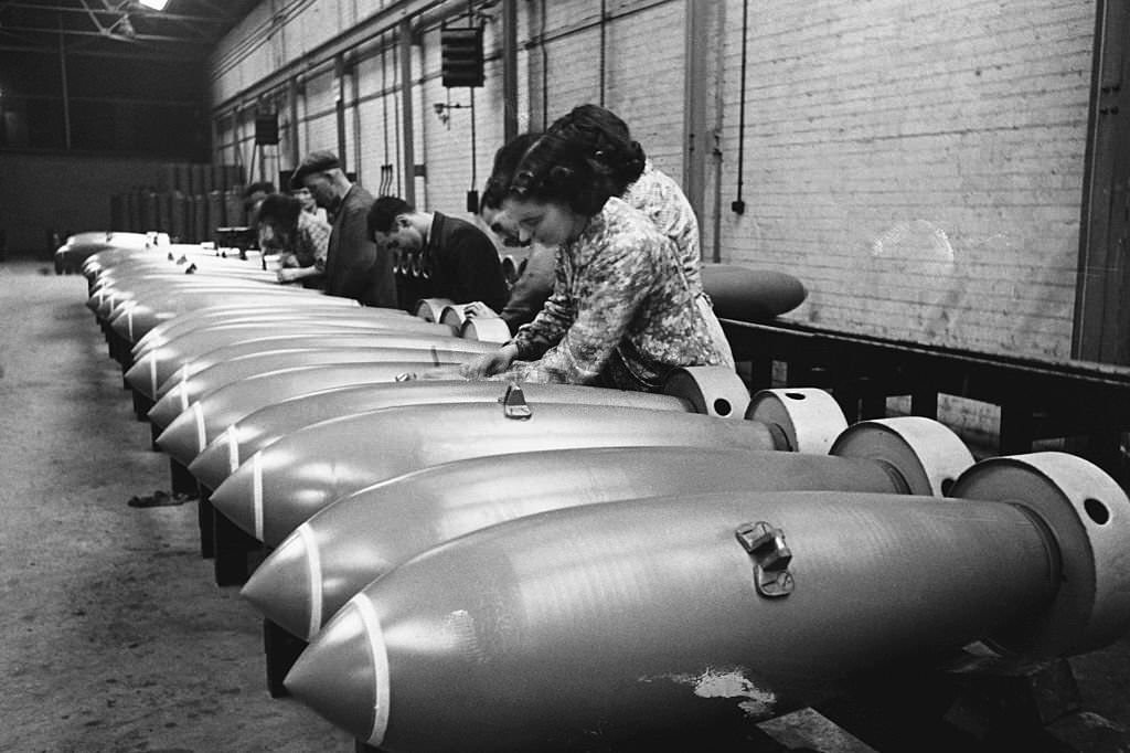 #64 Munition workers at a RAF munition factory fit the components to bombs.
