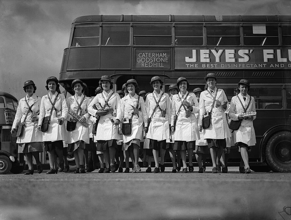 #76 The first women bus conductors all wearing their uniforms and holding equipment as they walk to their buses at a London transport depot during World War Two