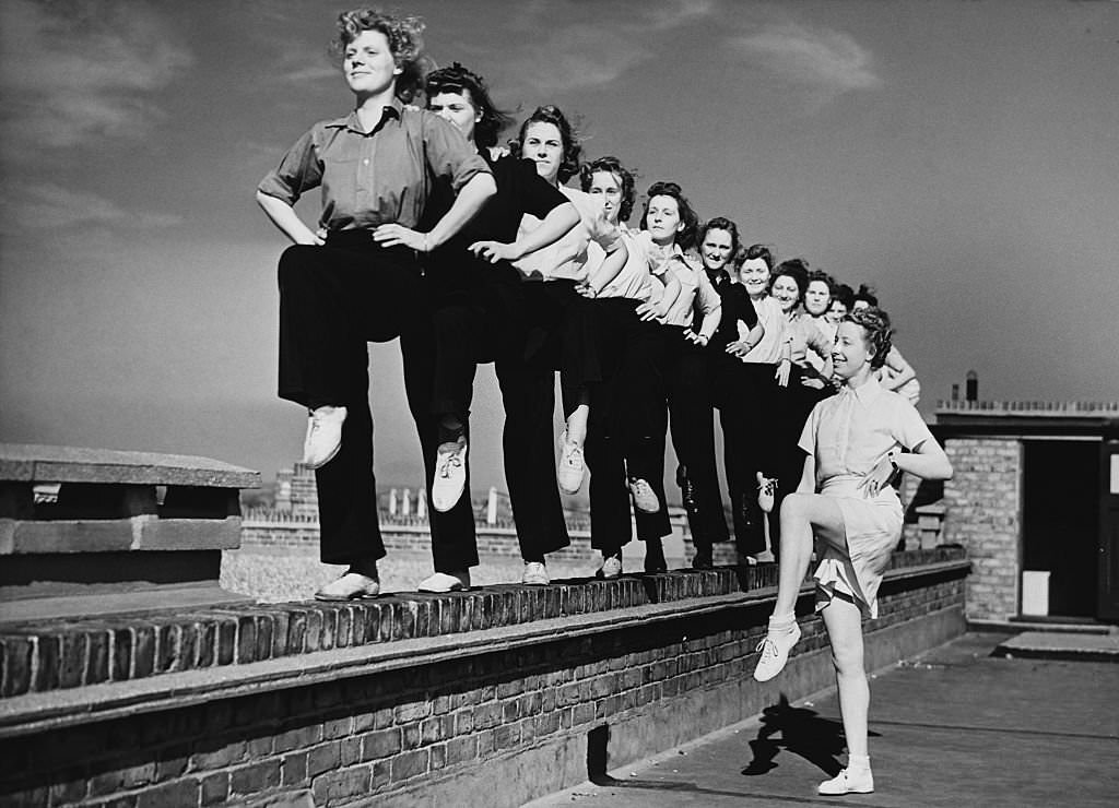 #90 Women firefighters exercise on the roof of their headquarters in Walthamstow, 1944.