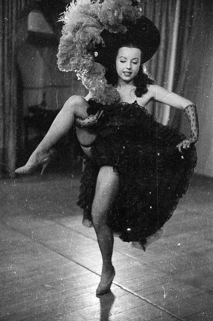#49 The chorus line at the Folies Bergere performing high kicks while dancing to ‘Gaite Parisienne’, 1955.