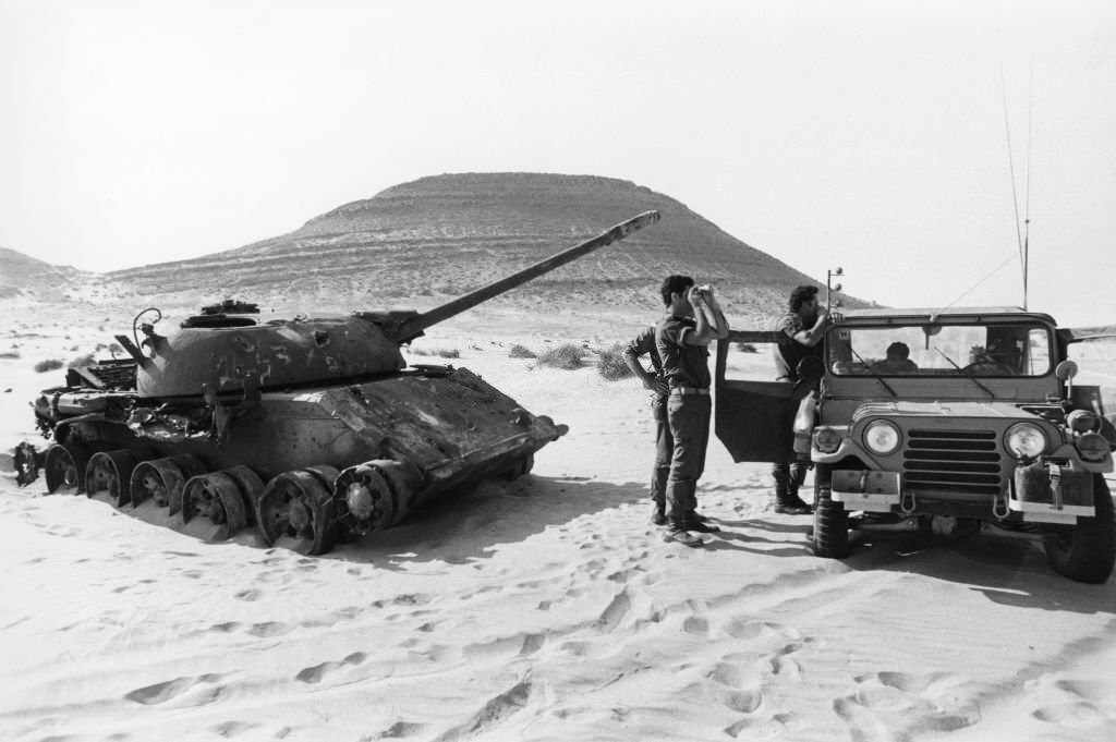#151 An Israeli tank exercise next to an Egyptian tank destroyed in June 1967 in the Sinai desert, 1978