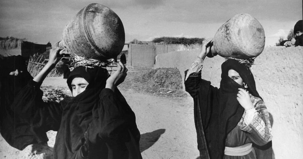 #49 Veiled women from a village near Luxor (Egypt) carry water jars on their heads, 1972