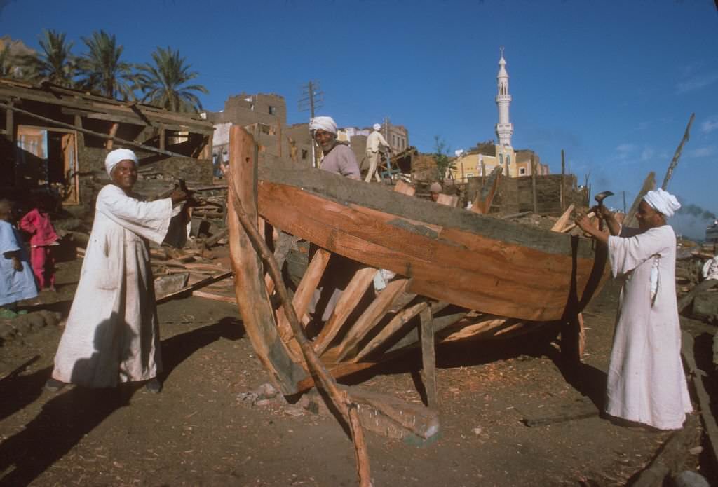 #14 Men building boats in a shipyard by the Nile River.