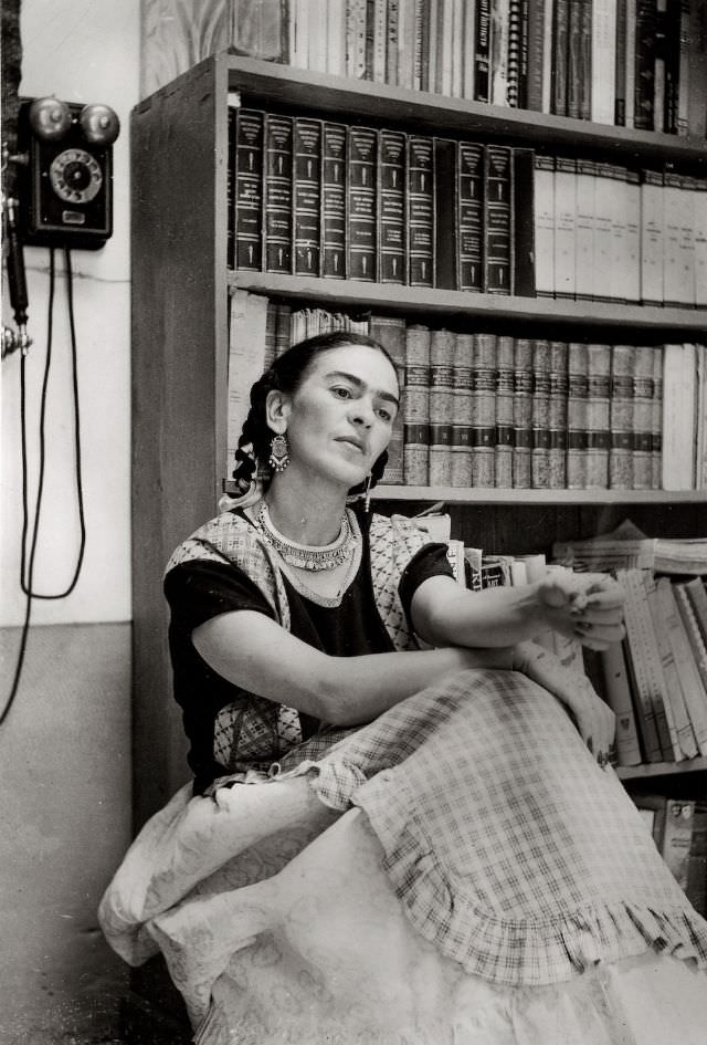 #16 Frida Kahlo in the Library of the Blue House, 1949.