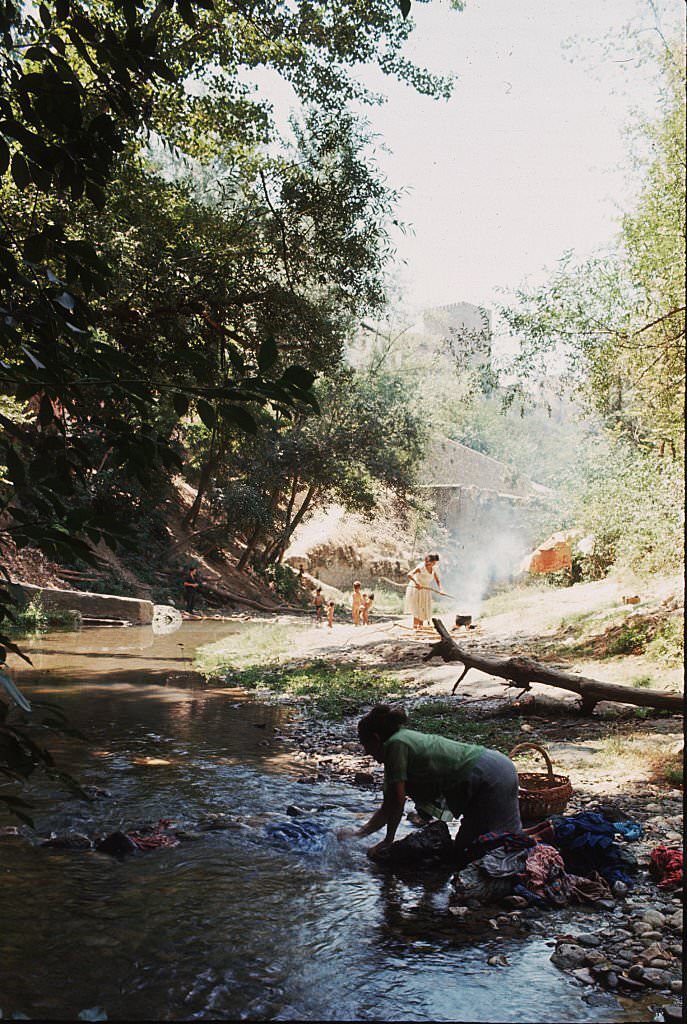 #25 A woman washes clothes in the Rio Darro, beneath the towers of Granada, Spain.