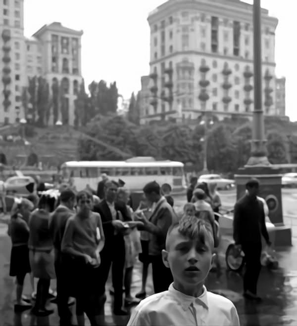 #51 Boy with mohawk haircut at the Khreshchatyk in Kyiv. In the back children, a bus and houses.