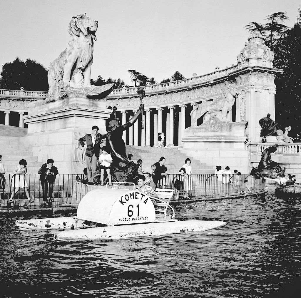 #82 A pedalo on a boating lake in front of the Monument to Alfonso XII in the Retiro approximately during the 1960s in Madrid, Spain.