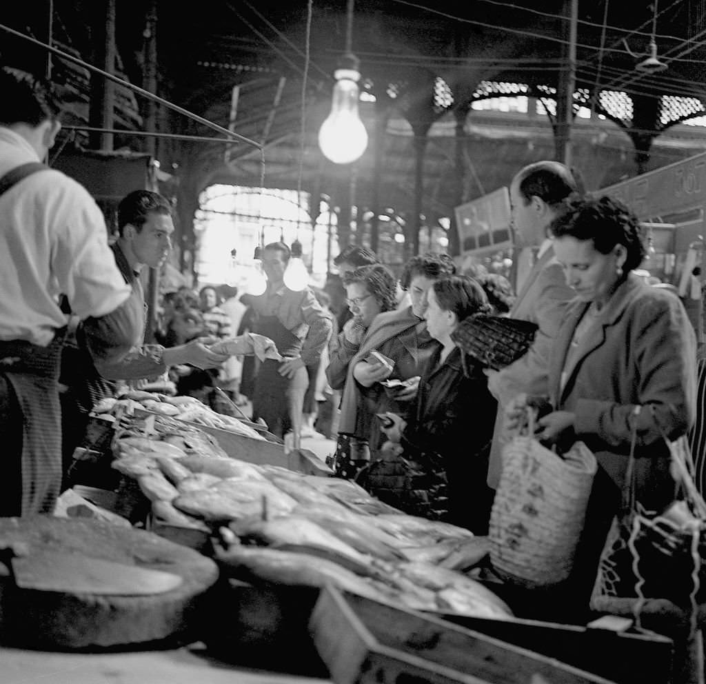 #84 People shop at a fish market during the 1960s in Madrid, Spain.