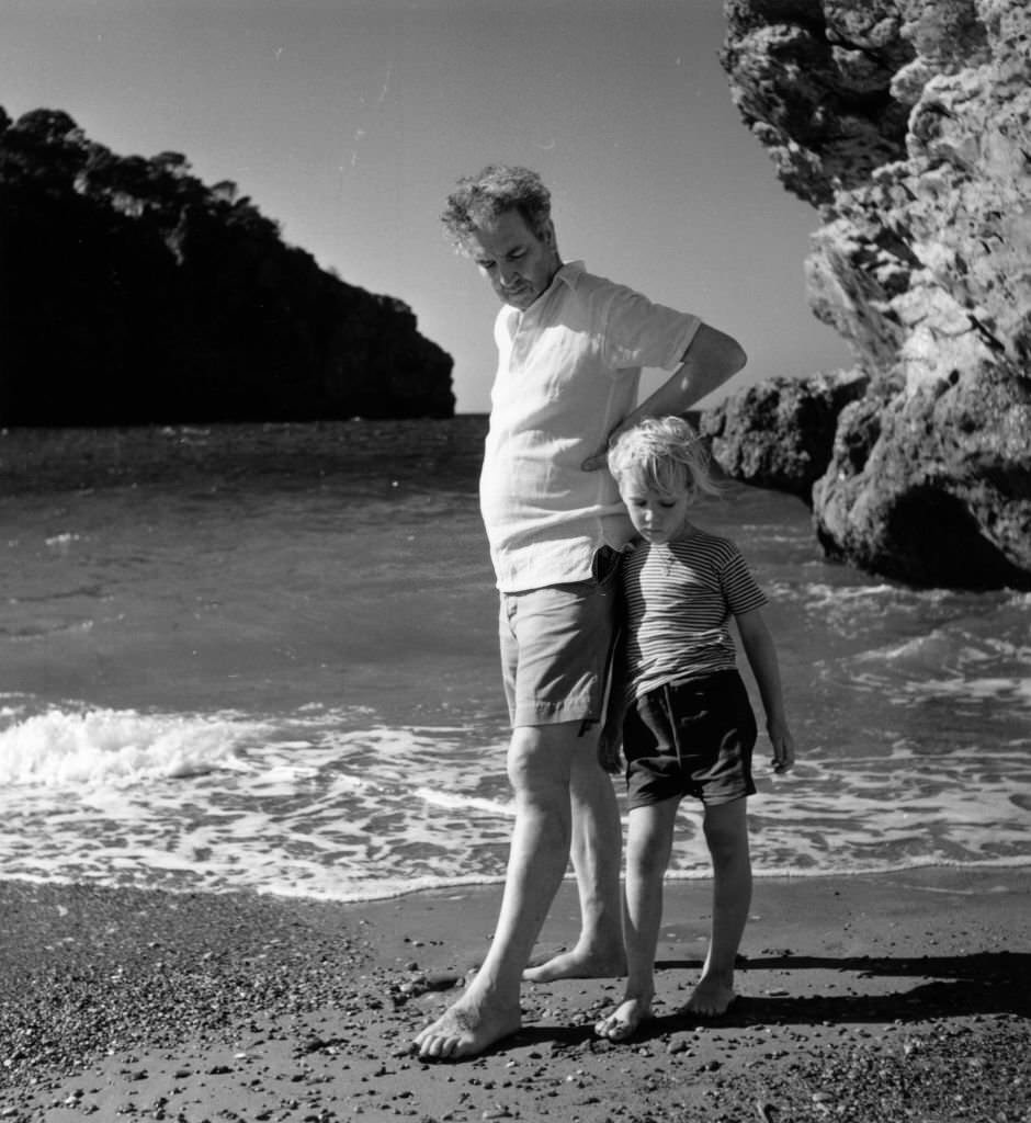 #113 Robert Graves on the beach at Deya, Majorca, with his son Juan, 1954