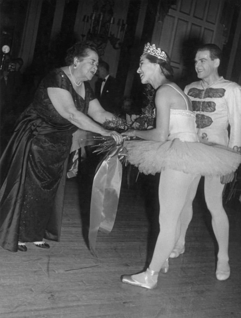 #98 Elsa Maxwell hands a bouquet of flowers to Maria Tallchief after her performance at Maxwell’s ‘Eight Ball’ party at the the Waldord-Astoria Hotel, 1950