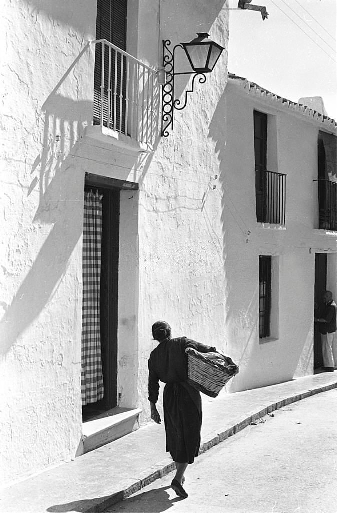 #15 Spain. Woman carrying a basket in a tipical street .